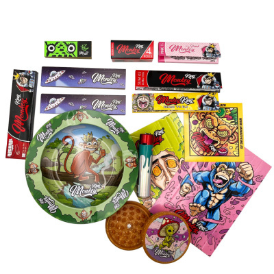 Acessórios para fumar King Monkey com papéis de enrolar, cinzeiro verde, isqueiro, folhas decorativas e moedor castanho.
