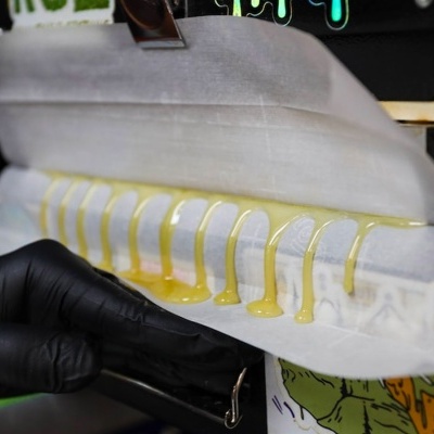 Tiras amarelas em papel antiaderente a sair de máquina com mão de luva preta a ajustar