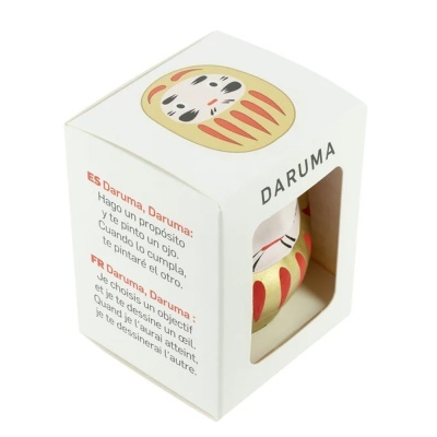 Caixa de embalagem com figura Daruma dourada visível por uma janela
