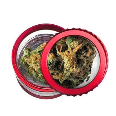 Triturador de ervas vermelho com tampa transparente e erva seca verde dentro