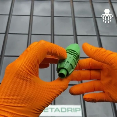 Mãos com luvas laranja segurando bocal verde com relevo