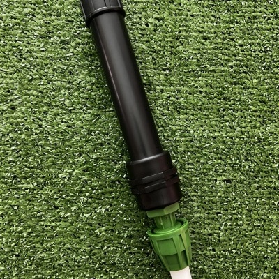Irrigador preto e verde sobre relva sintética verde