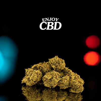 Botões de cânhamo secos castanhos claros com texto ENJOY CBD em fundo preto