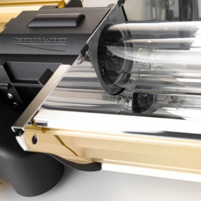 Lâmpada tubular com estrutura metálica dourada e preta próxima a uma janela