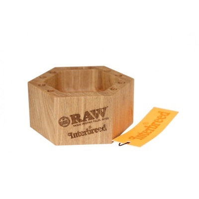 Cinzeiro hexagonal em madeira clara com texto gravado RAW Interbreedi e etiqueta amarela