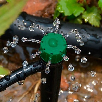 aspersor de rega verde e preto a pulverizar água no solo