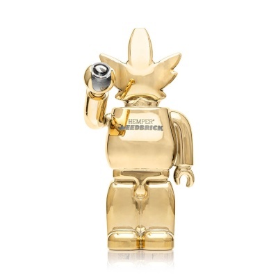 Figura dourada em forma de boneco com cabeça de folha e texto HEMPER WEEDBRICK
