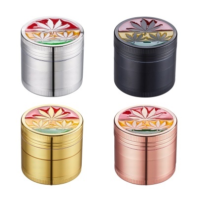 Quatro trituradores metálicos coloridos com folhas decorativas no topo