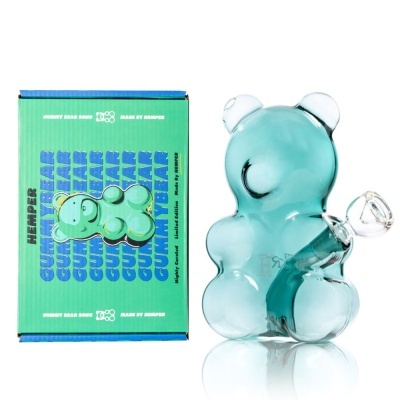 Bong de vidro azul em forma de urso junto a embalagem verde com texto e ilustração de urso.