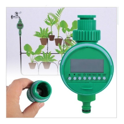 temporizador digital de rega verde com visor e botões, ligado a torneira para irrigação de plantas