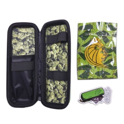 Estojo preto aberto com interior estampado, embalagem verde com folhas e logo de leão amarelo, e dois autocolantes.