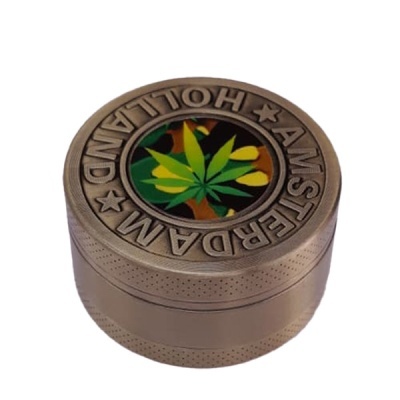 Triturador metálico bronze com palavras AMSTERDAM HOLLAND e desenho de folha verde de cannabis
