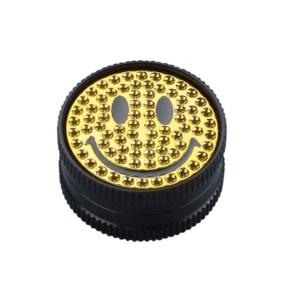 Peça circular preta com rosto sorridente dourado e rebites