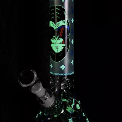 Base de vidro para fumar com estampas de rostos brilhantes em verde e azul e uma figura principal com óculos de sol