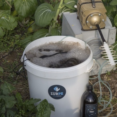 Balde branco com líquido espumoso e dispositivo metálico ao ar livre