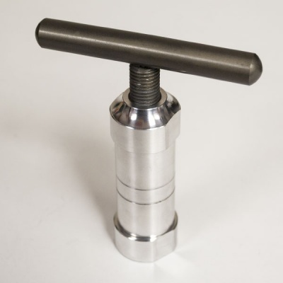 Ferramenta metálica cilíndrica com alavanca preta fosca sobre superfície branca