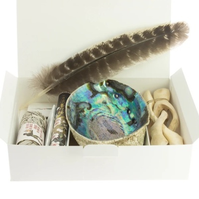 Conjunto de incenso e acessórios, incluindo sálvia, incenso e recipiente abalone numa caixa branca aberta.