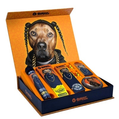 Conjunto de produtos G-ROLUZ com imagem de cão com tranças em embalagem cor de laranja e azul