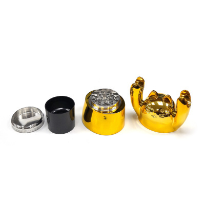 Conjunto de triturador metálico dourado e preto desmontado sobre fundo branco.