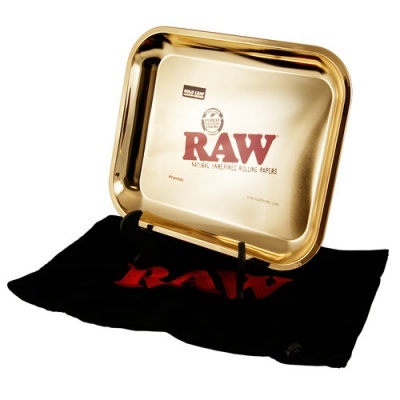 Tabuleiro dourado RAW sobre pano preto com texto vermelho