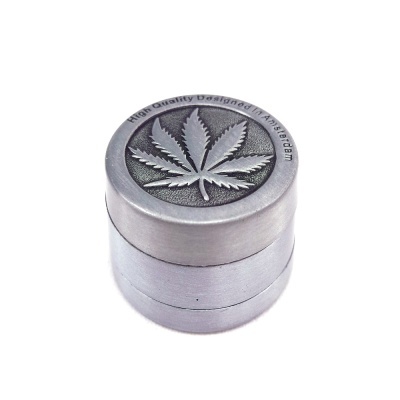 Moinho de ervas em metal prateado com folha de cannabis em relevo