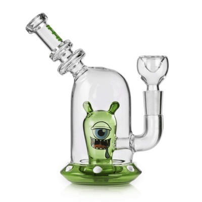 Acessório de vidro para fumar com personagem verde de um olho e base verde com pontos brancos.