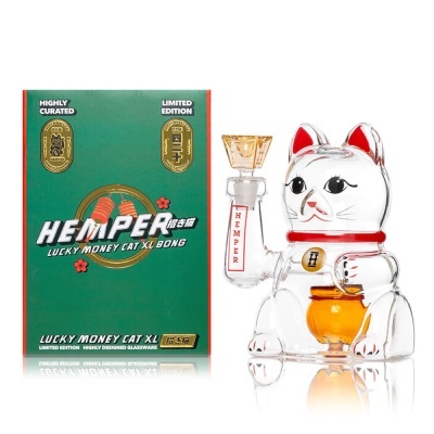 Bong de vidro em forma de gato da sorte ao lado de embalagem verde com texto