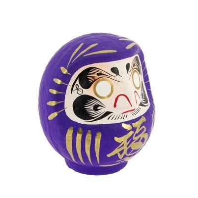 Daruma roxo com detalhes dourados e face pintada