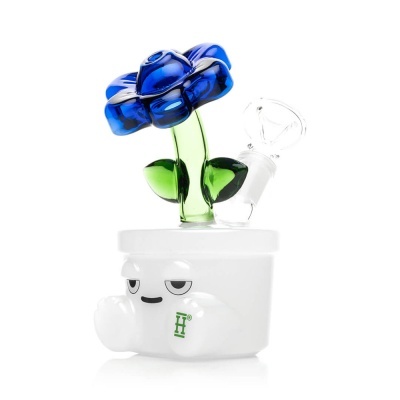 Base branca com rosto e letra H verde, tubo de vidro verde com flor azul transparente e acessório de vidro