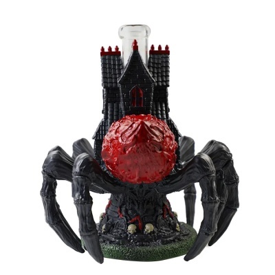 Figura decorativa de aranha com casa castelo e esfera vermelha.