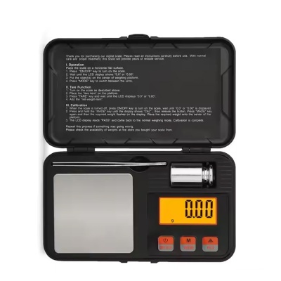 Balança digital com estojo preto e visor amarelo exibindo 0.00 g