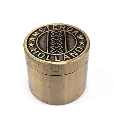 Triturador de metal cor de bronze com inscrições e design gravado no topo