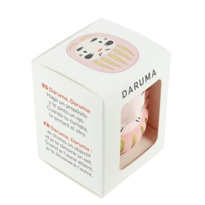Caixa com figura Daruma cor-de-rosa e texto explicativo em espanhol e francês