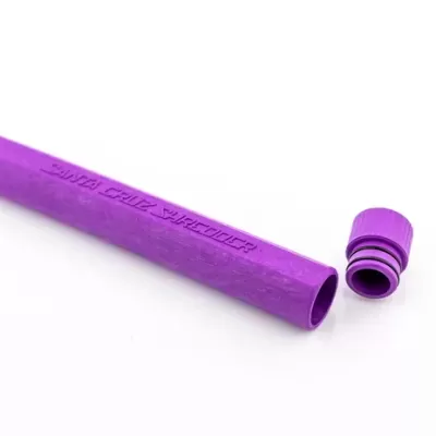 Recipiente tubular roxo com tampa destacada ao lado sobre fundo branco