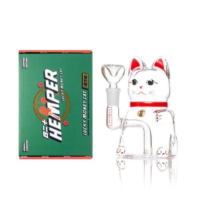 Cachimbo de vidro transparente em forma de gato da sorte ao lado de caixa verde com texto