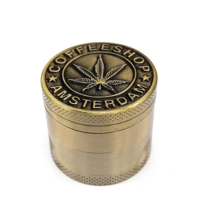 Moedor metálico dourado com gravação de folha de cannabis e texto COFFEESHOP AMSTERDAM