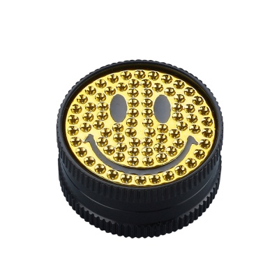 Peça circular preta com rosto sorridente dourado e rebites