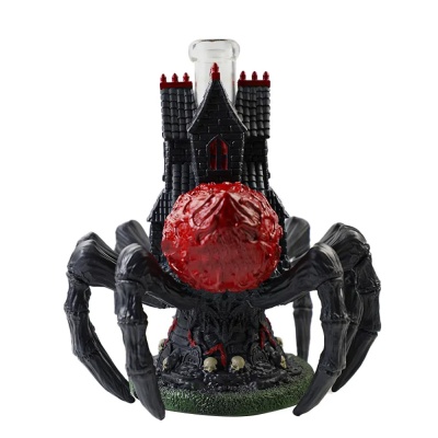 Figura decorativa de aranha com casa castelo e esfera vermelha.
