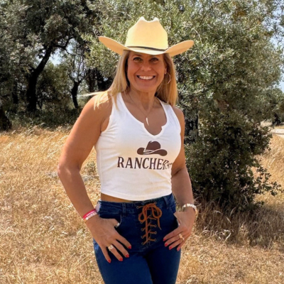 Mulher com chapéu de cowboy bege e t-shirt branca RANCHER em campo rústico