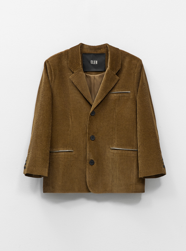 Khaki corduroy blazer Casaco masculino castanho em veludo cotelê com botões e bolsos frontais, pendurado numa parede branca.