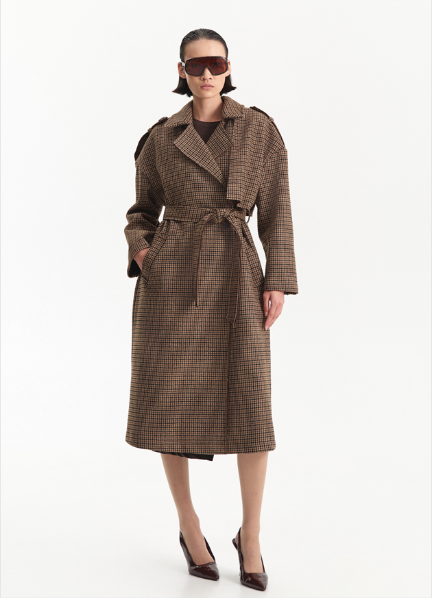 Houndstooth trench coat Mulher a usar sobretudo comprido xadrez castanho com cinto, sapatos de salto e óculos escuros.