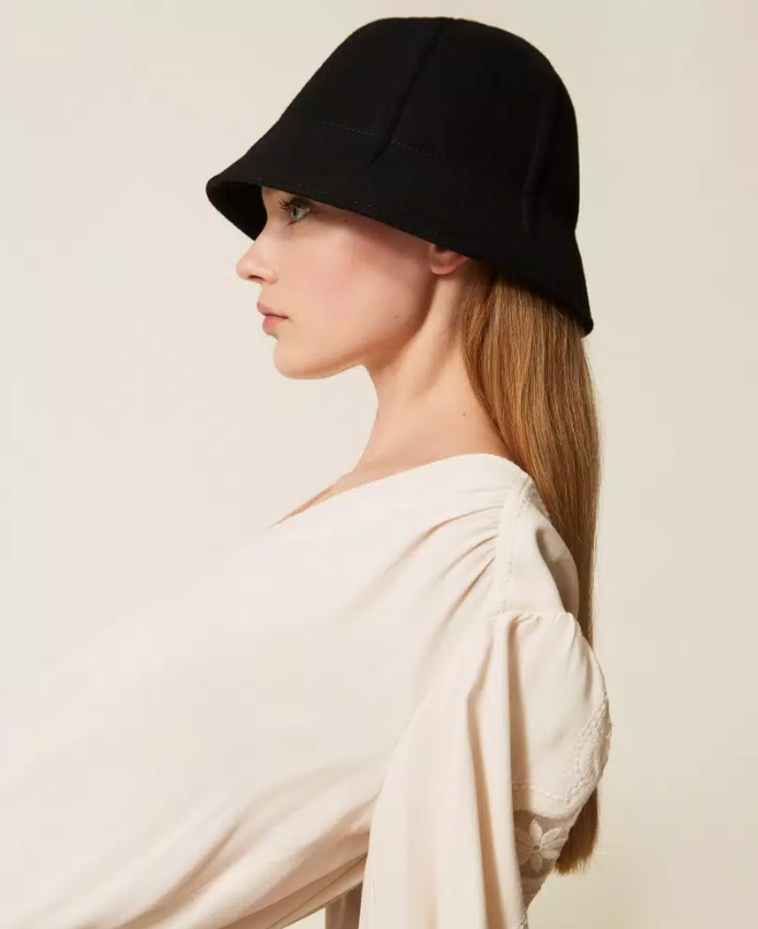 Wool cloth hat Mulher de perfil usando chapéu preto tipo balde e blusa clara com mangas bufantes