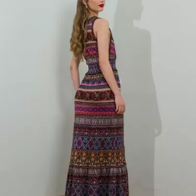 Vestido comprido étnico colorido usado por mulher de cabelos ondulados, vista lateral de costas