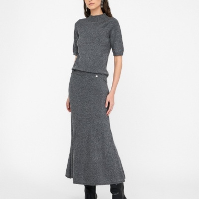 Conjunto feminino cinzento de malha com camisola e saia comprida, usado com botas pretas.