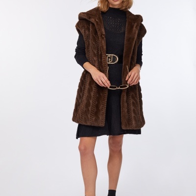 Mulher vestindo casaco de pelo castanho, vestido preto e sapatos pretos com meias pretas 