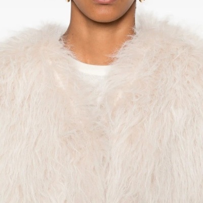 Casaco peludo creme feminino com top branco e brincos de argola prateados