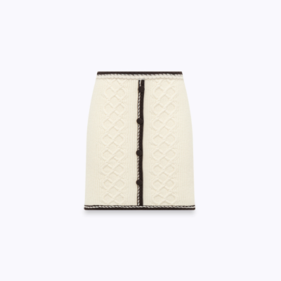 Saia curta creme de malha com padrão de tranças e botões pretos no centro