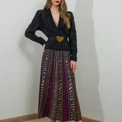 Mulher com blusa preta e saia longa colorida com sapatos pretos