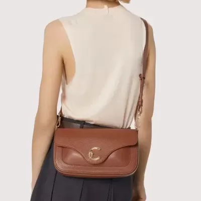 Bolsa castanha de pele com fecho dourado usada por uma pessoa vista de costas