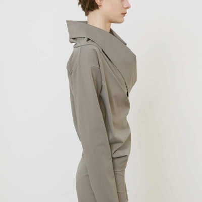 Pessoa de perfil com casaco cinza de gola ampla e saia cinza.